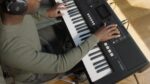 Yamaha PSR-E483, teclado portátil de 61 teclas sensible al tacto con sonido, atril para partituras y adaptador de corrie